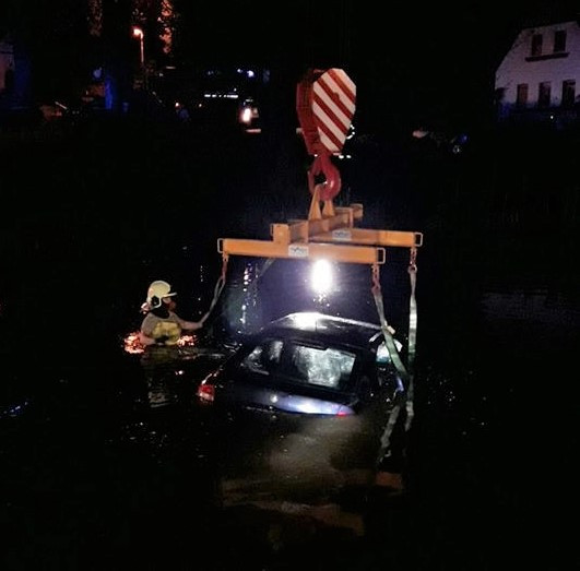 Hasiči vyprošťují auto ze dna rybníka pomocí jeřábu