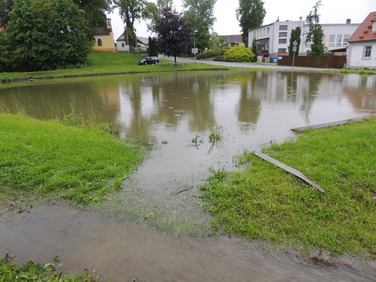Nejenom dole kolem řeky, také na kopci jde do tuhého. Po ránu v Hůrách začal přetékat návesní rybník. Starostka zorganizovala SDH a hasiči situaci bravurně zvládli. Foto Tomáš Kubín