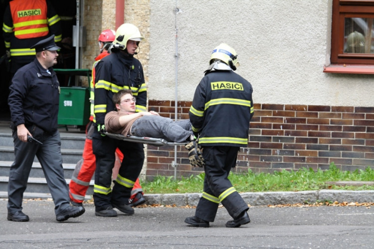 Hasiči odnášejí zraněného