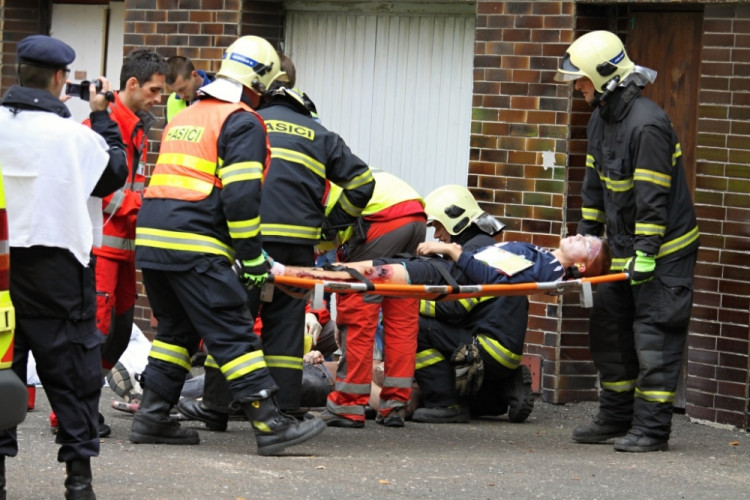 Hasiči odnášejí zraněného