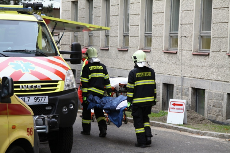 Hasiči odnášejí zraněného