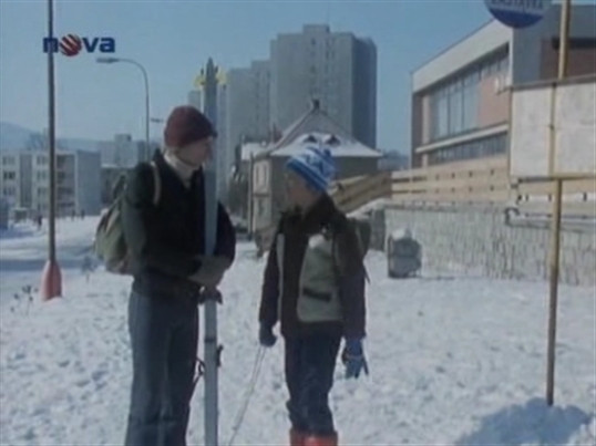 Trochu oříšek. Karfík čeká na autobus a potká svého žáka Jokla. Jenže tady žádná zastávka ve skutečnosti není, také tu vyrostlo už pár stromů. Jsme v Jabloňové ulici.