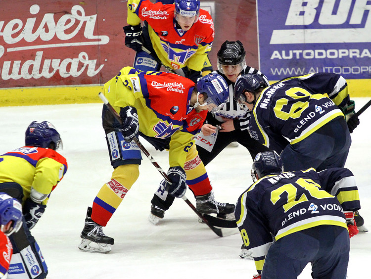 Rozhodčí háže puk mezi hokejky Galamboše a Najmana