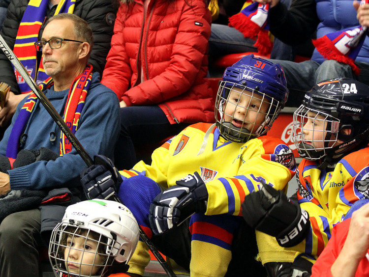 Malí hokejisté čekající na svůj čas na ledě zatím mezi diváky