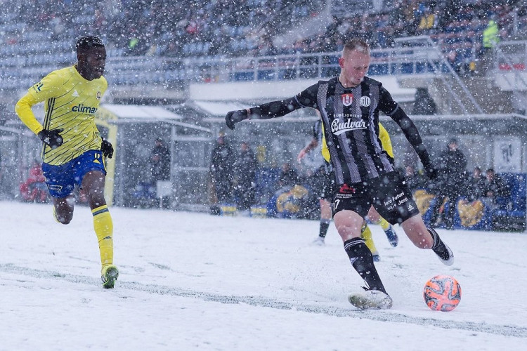 Ondřej Mihálik (v černém) posílá míč před branku. 