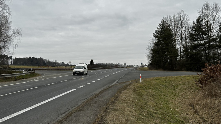 Chodci jdou od zastávky po tomto úzkém chodníčku až do obce, zatímco kolem nich sviští automobily vysokou rychlostí