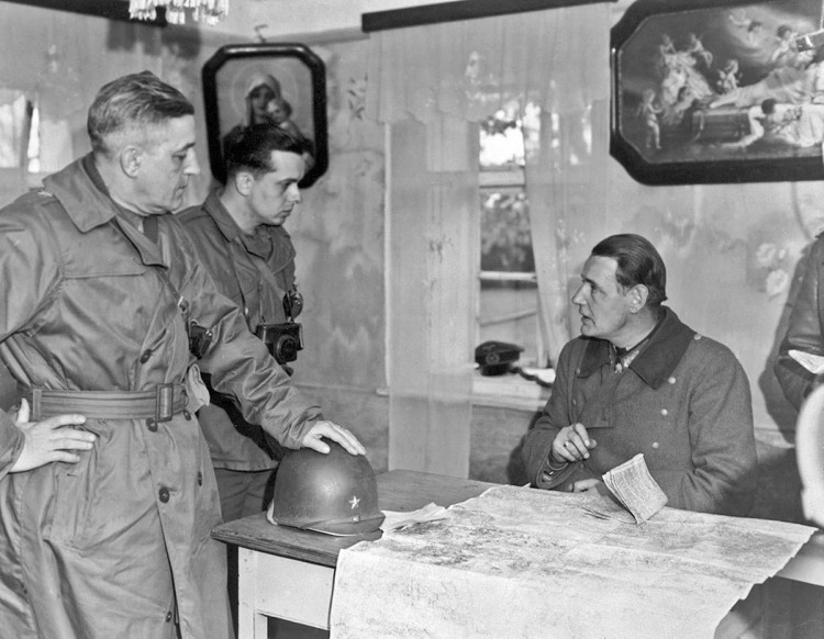 Velitel 90. pěší divize genmjr. Earnest dojednává podmínky kapitulace divize. Vedle generála stojí kapitán, který tlumočí. Sedící genpor. von Wietersheim. Skrze okno je vidět silueta kostelíka sv. Anny