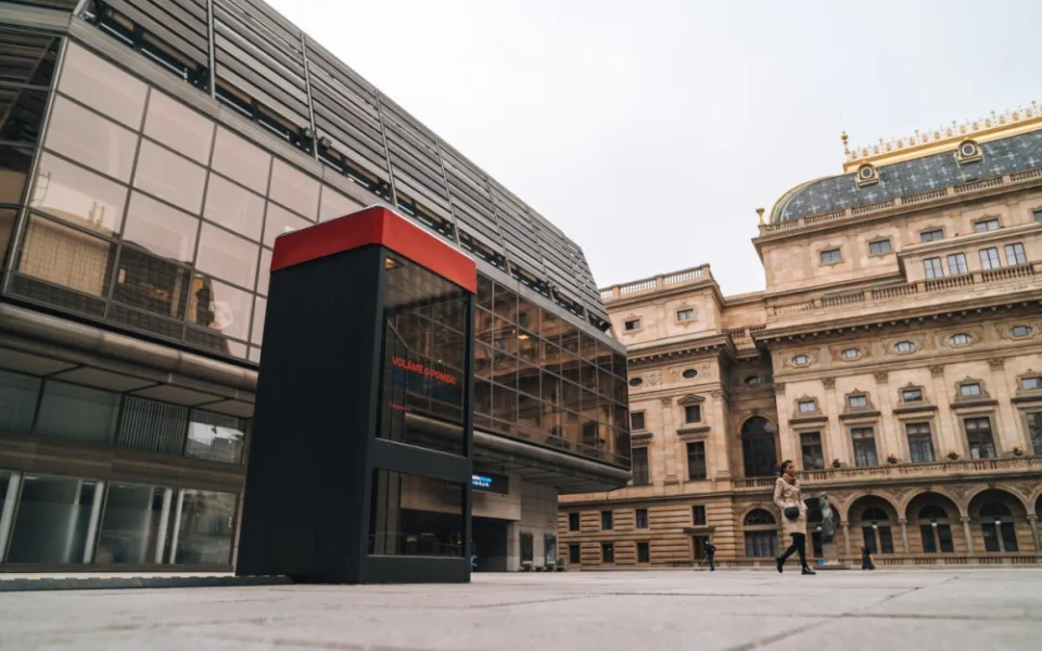 U Národního divadla stojí telefonní budka. Vypráví příběhy lidí v nouzi.
